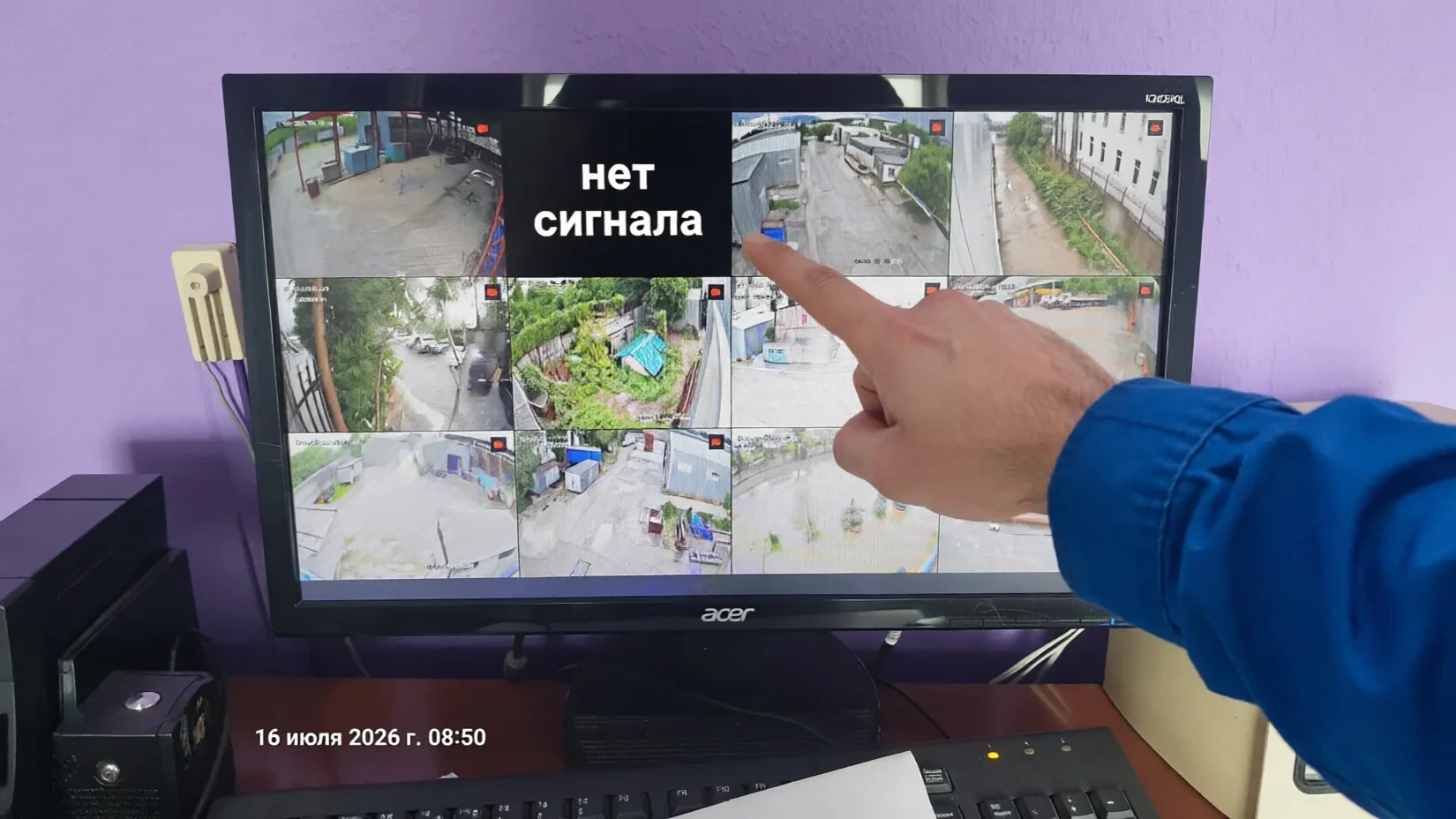 Монитор системы видеонаблюдения: одна из камер не работает — чёрный экран с надписью "нет сигнала", рука инженера указывает на проблему